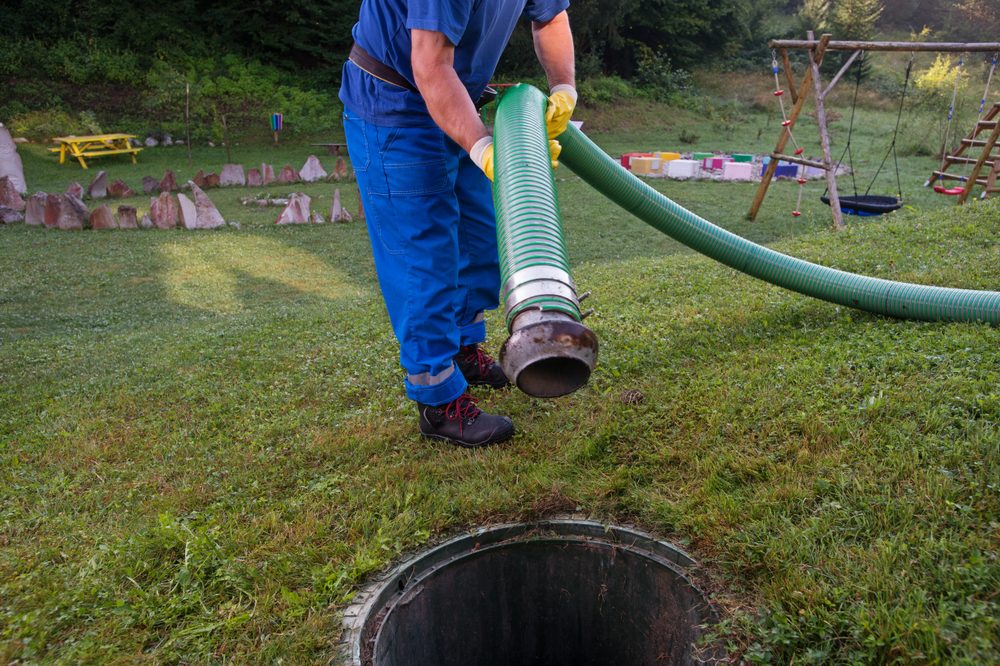 Technician lowers pumping hose into septic tank opening